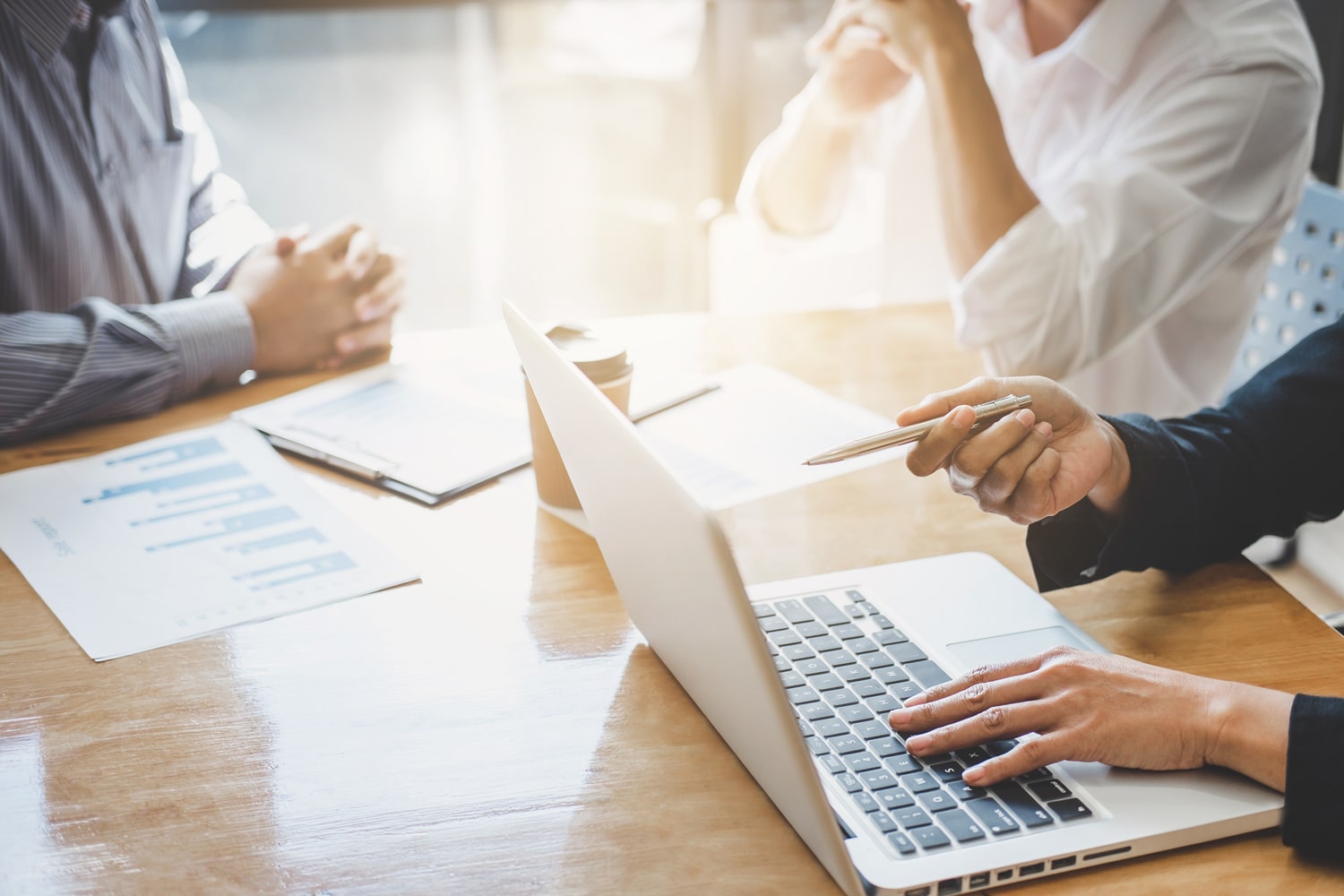 person working on a laptop having a meeting with two other people